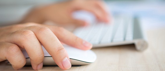 A person's hand is using a computer mouse to book online.