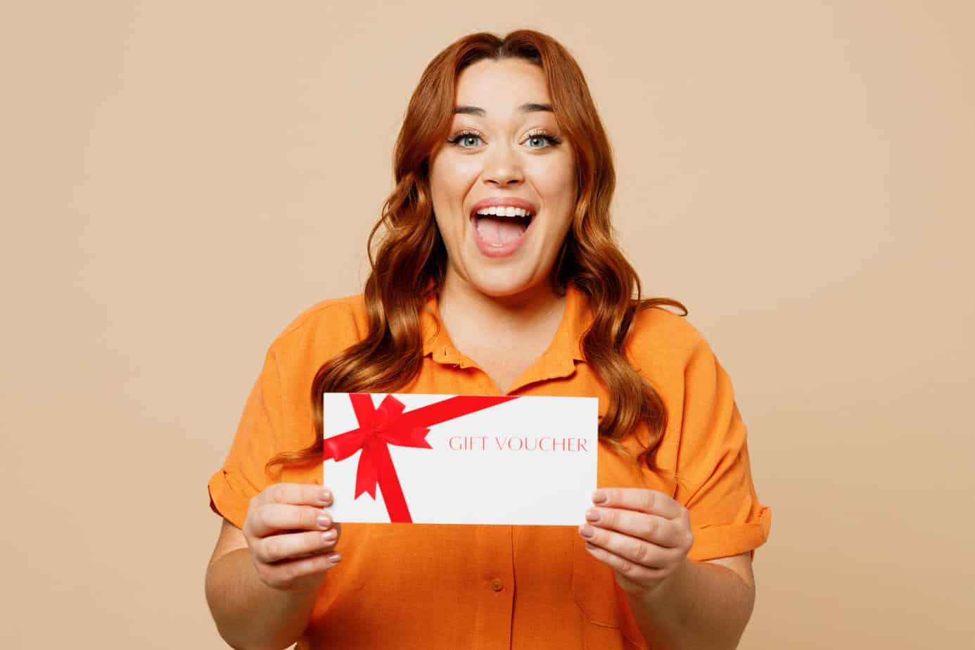 A woman holding up a gift certificate on a beige background.