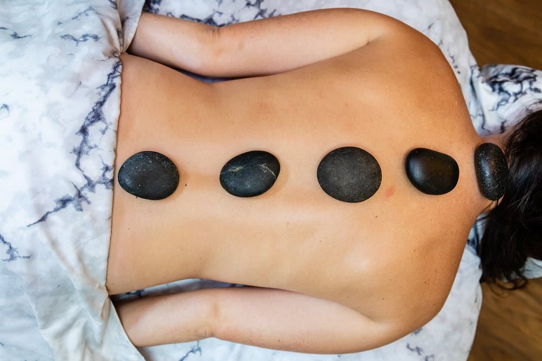 A woman getting a hot stone massage on her back.